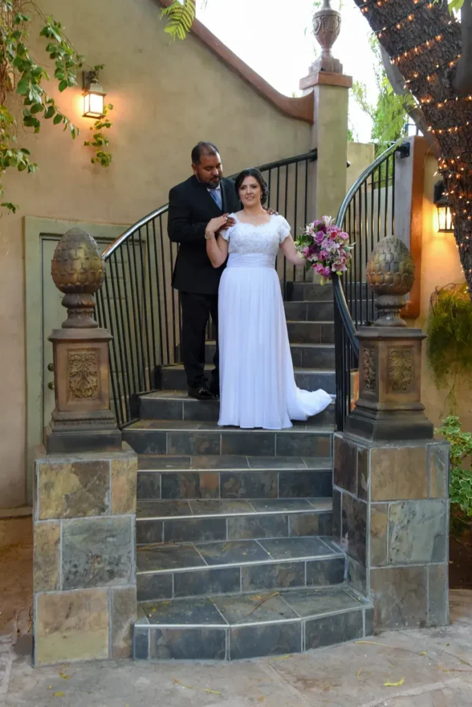 Pareja de novios posando en escalinata de piedra con ramo de flores en Gilbert, Arizona.